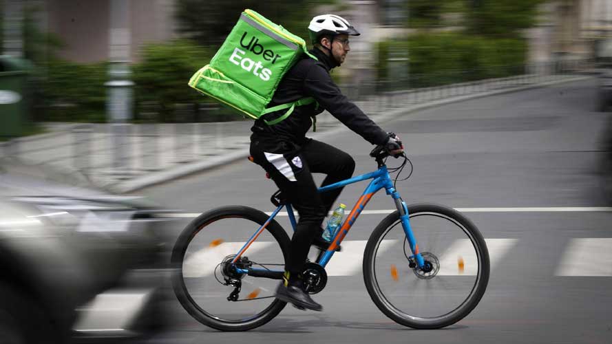 Foto de um entregador de bicicleta com a bag da Uber Eats em verde