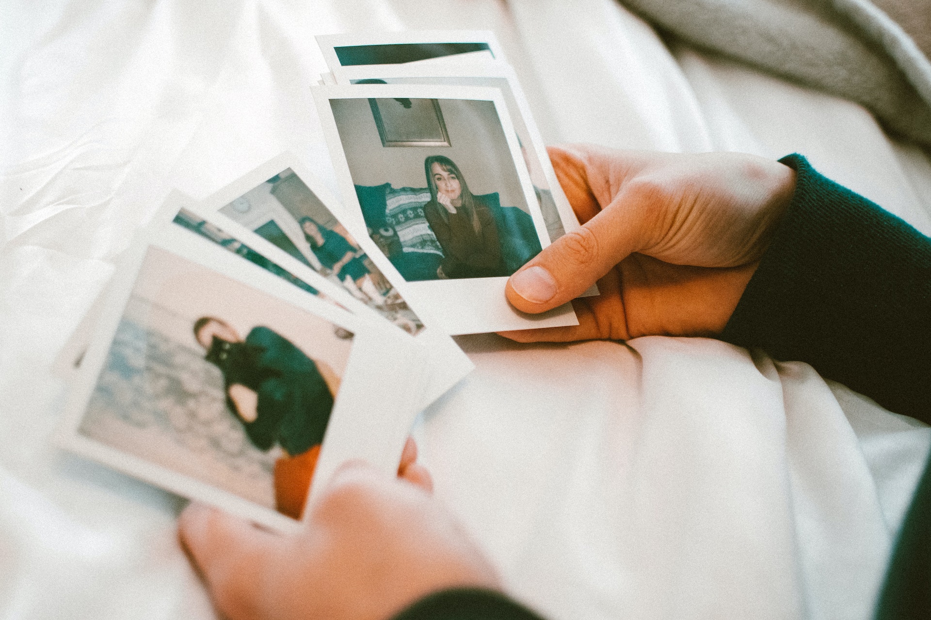 Hands sort through old polaroid photos.