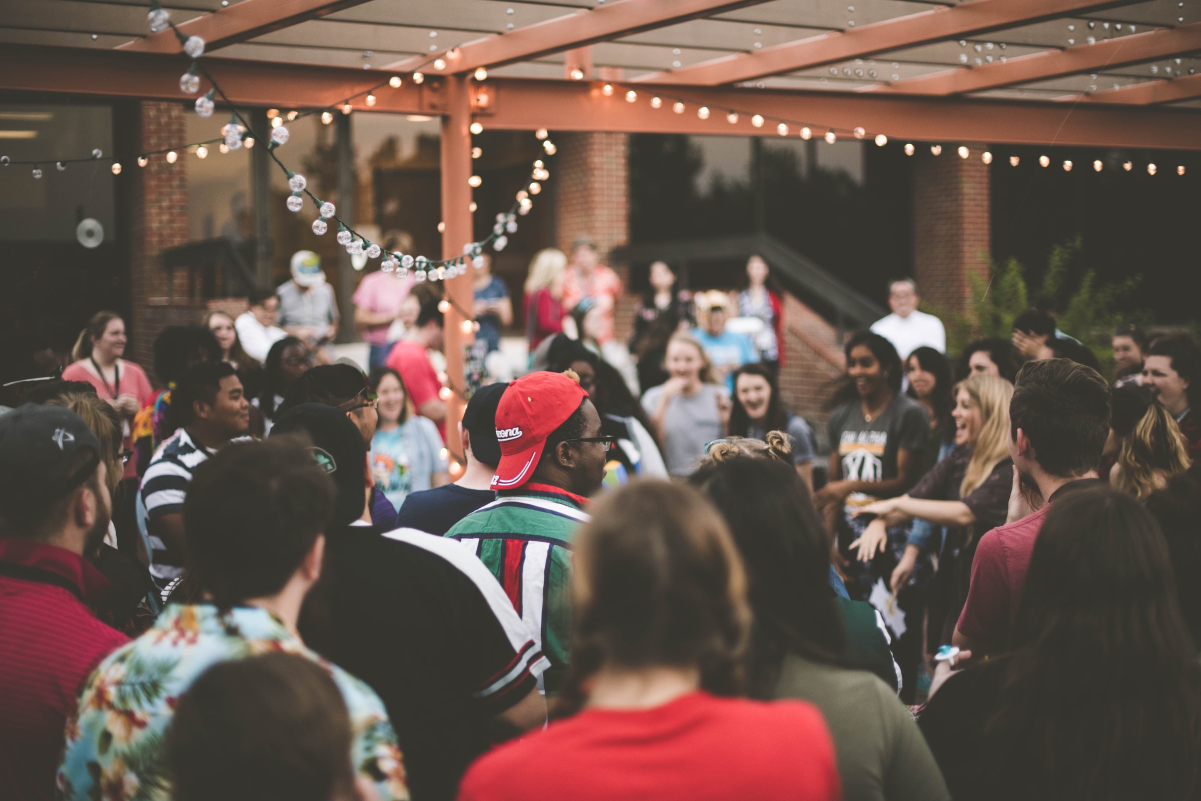 A crowd of people gather for a party on an outdoor patio.