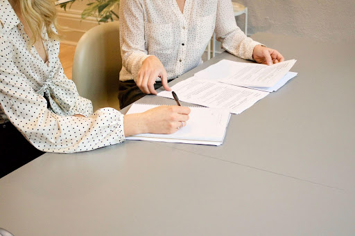 Deux femmes assises côte à côte discutent et prennent des notes.