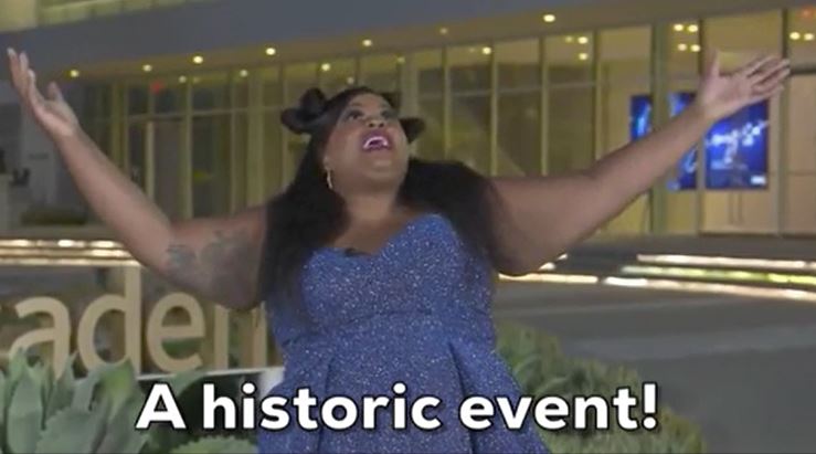 une femme lève les bras et dis " a historic event !"