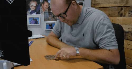 un homme compte ses pièces de monnaie à la main