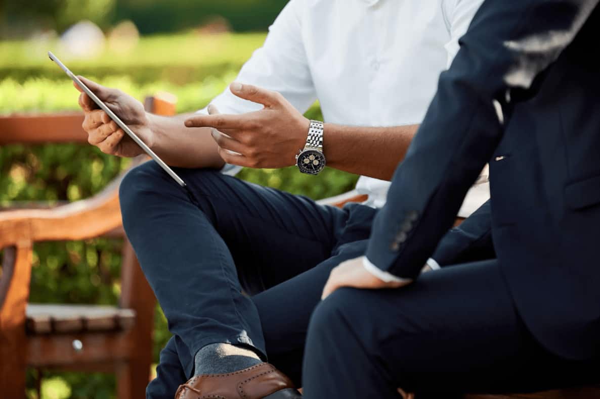 deux hommes en costumes regardent une tablette