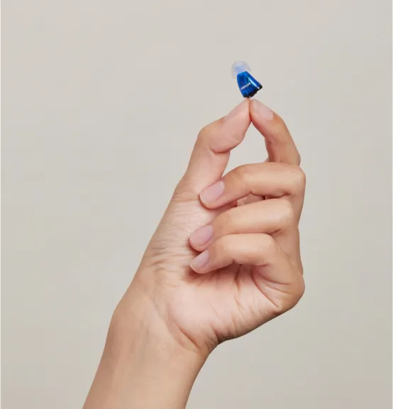 Hand holding in-ear hearing aid.