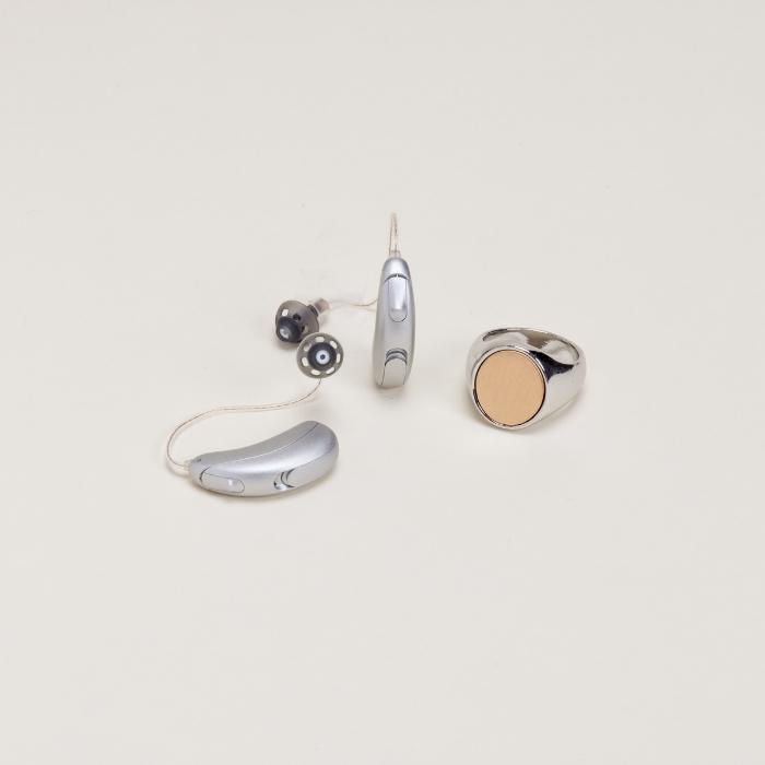 Audicus Clara hearing aids next to signet ring for size comparison