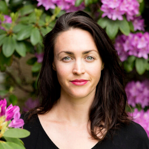 A photo of Katharine Bolton in front of purple flowers.