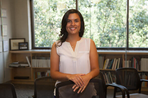 A photo of Carolina Uechi in front of a bookshelf.
