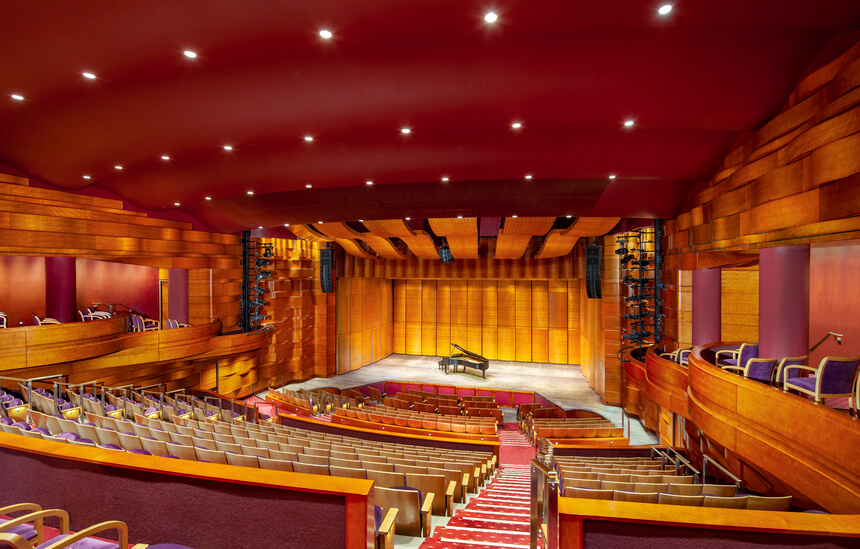 An interior photo of a theater with a piano on the stage.