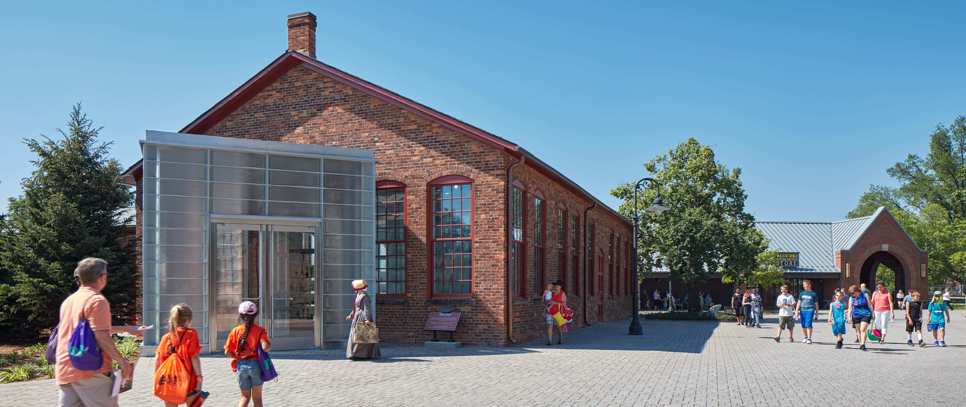 A photo of visitors walking towards a glass and brick building.