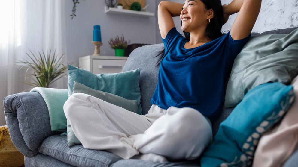 A woman sitting back and relaxing on comfy furniture.