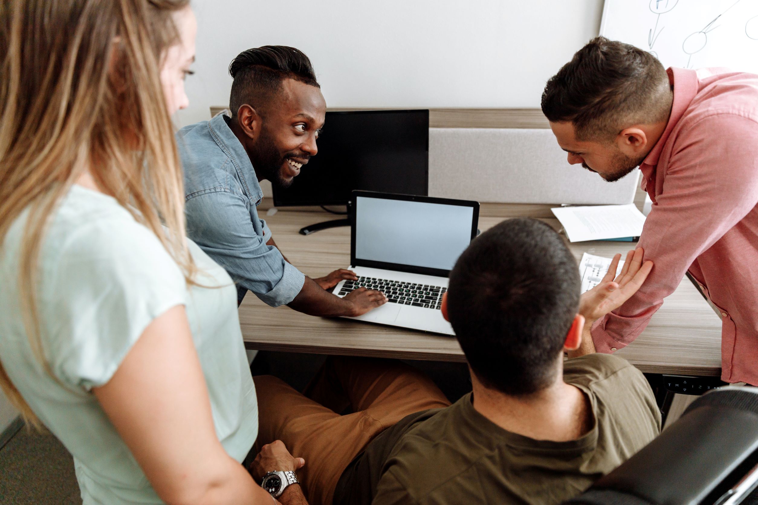 Team working together hunched over laptop