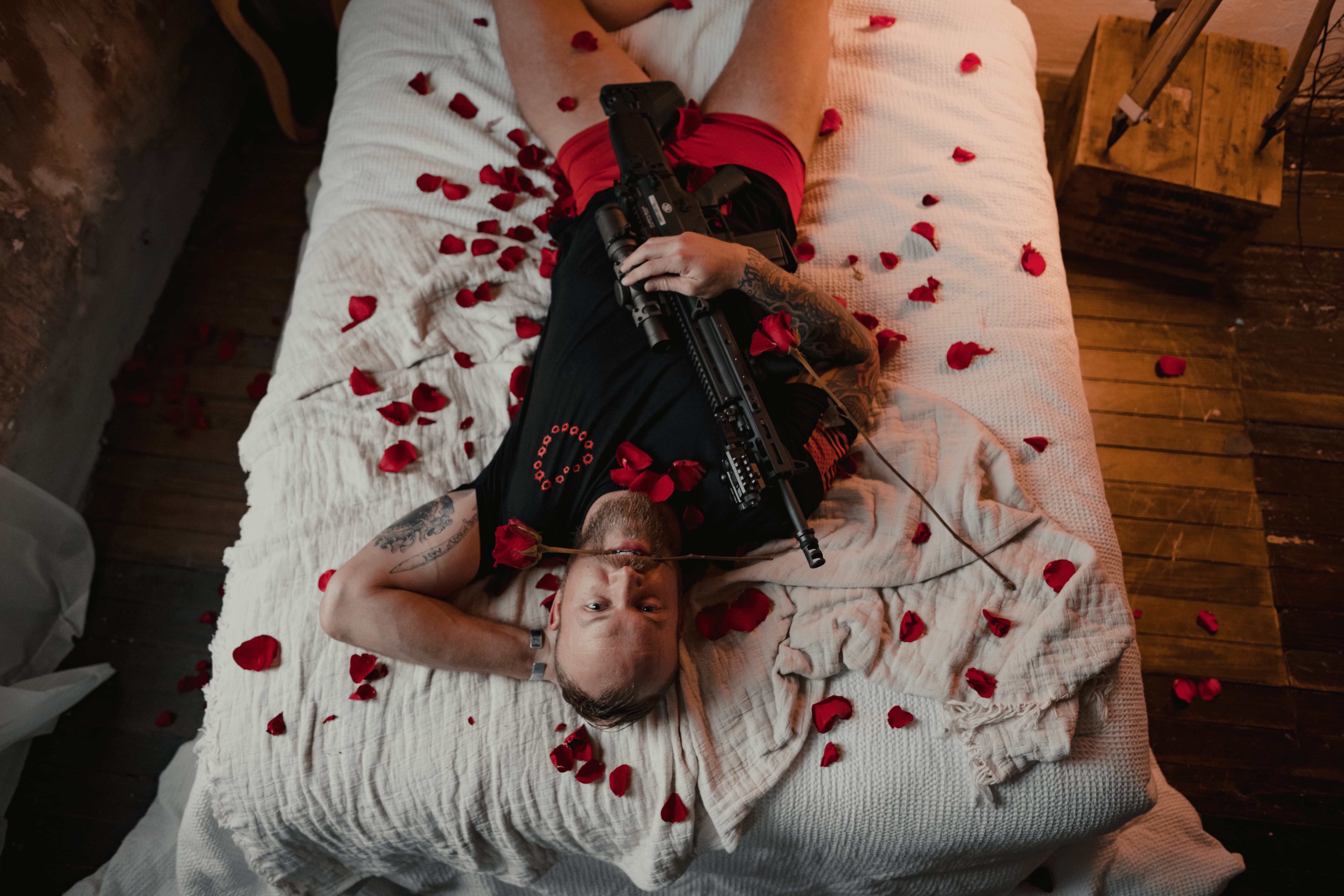 A man laying in a bed with a rose in his mouth.