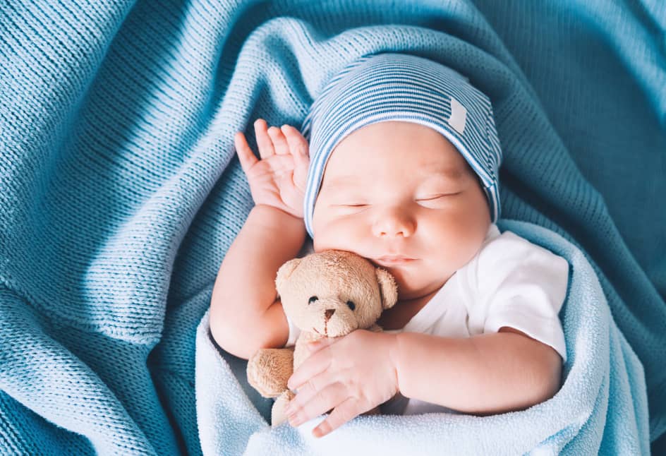 Baby sleeping wrapped in a blue blanket
