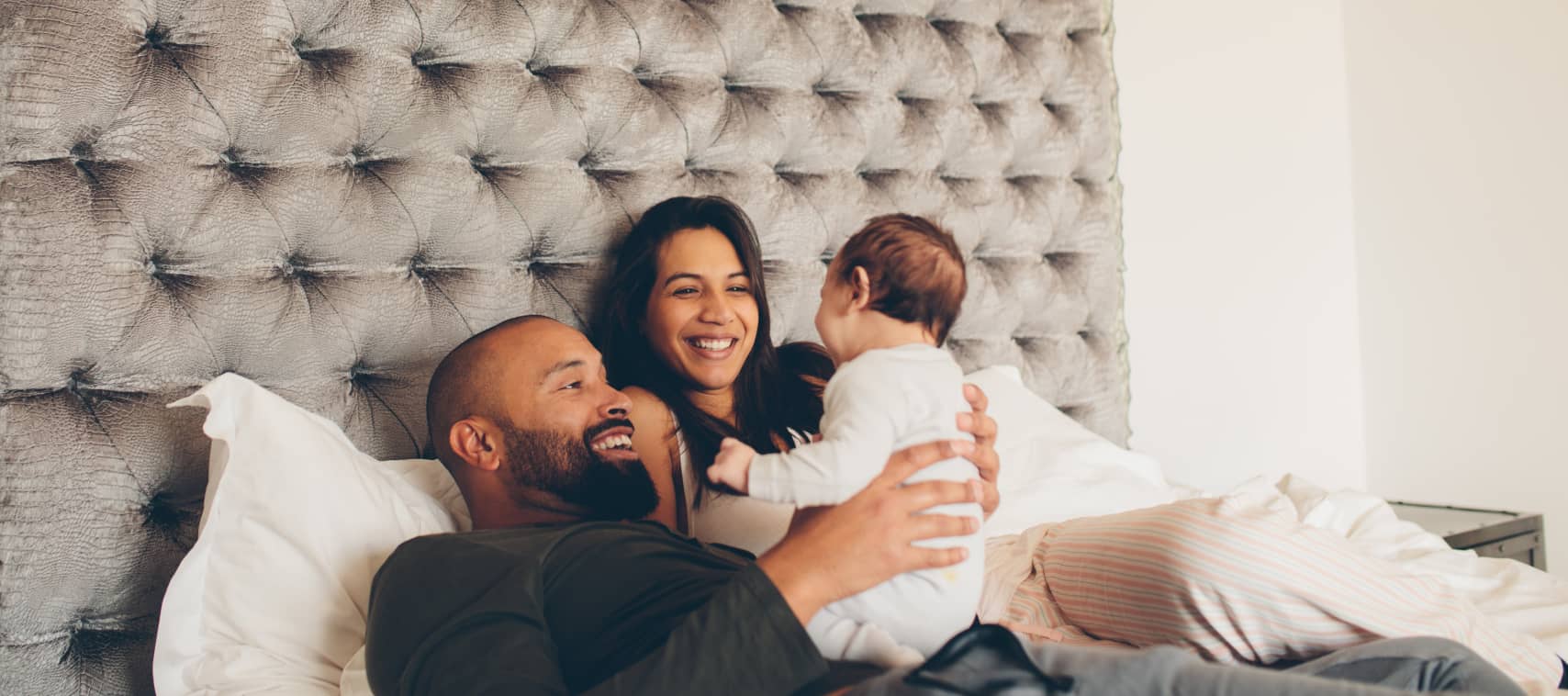 Couple holding baby high up in bed