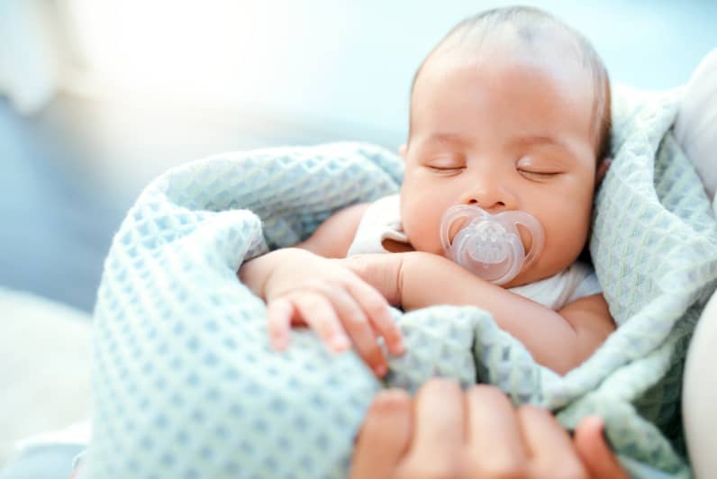 Sleeping baby with bib in mouth