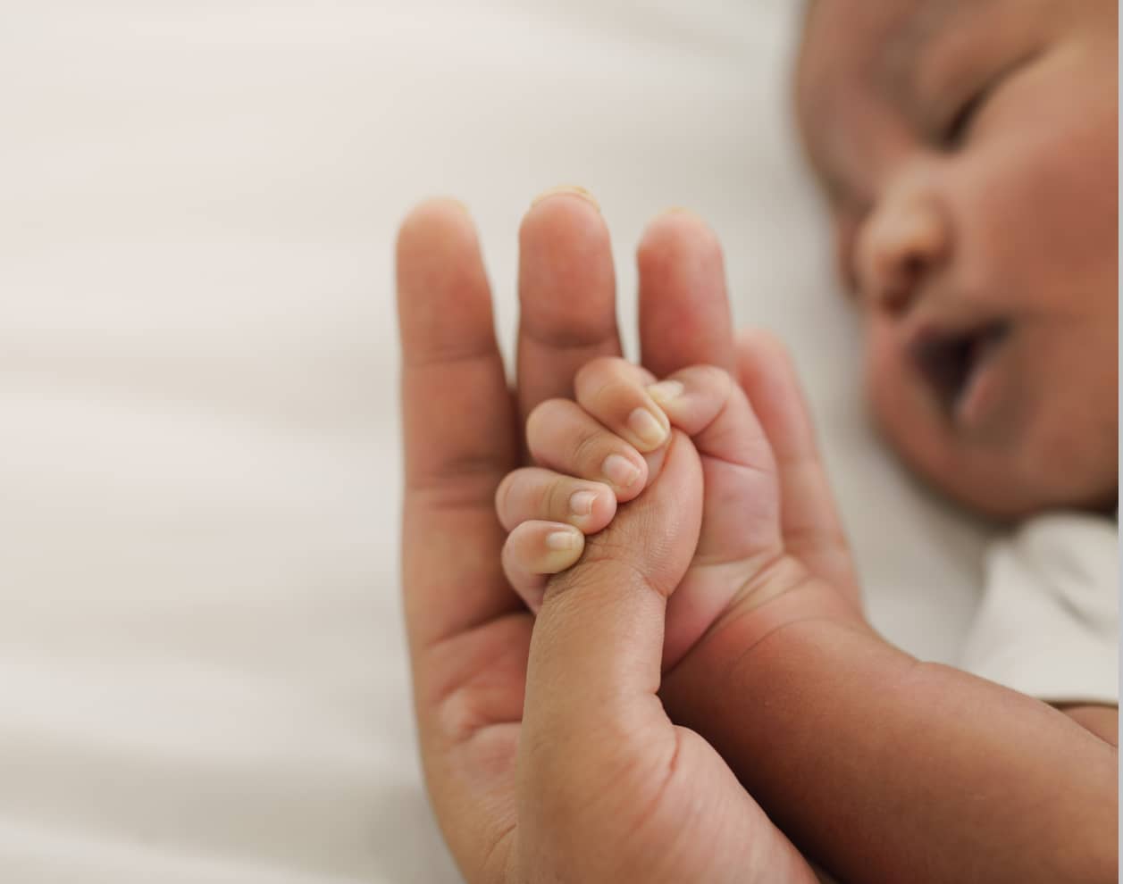 Baby grabbing parent's fingers while sleeping