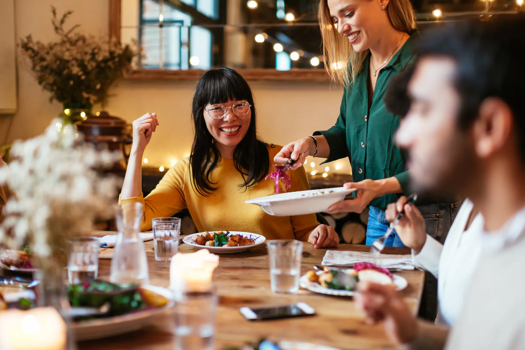 Party host laughing with friends, while having dinner