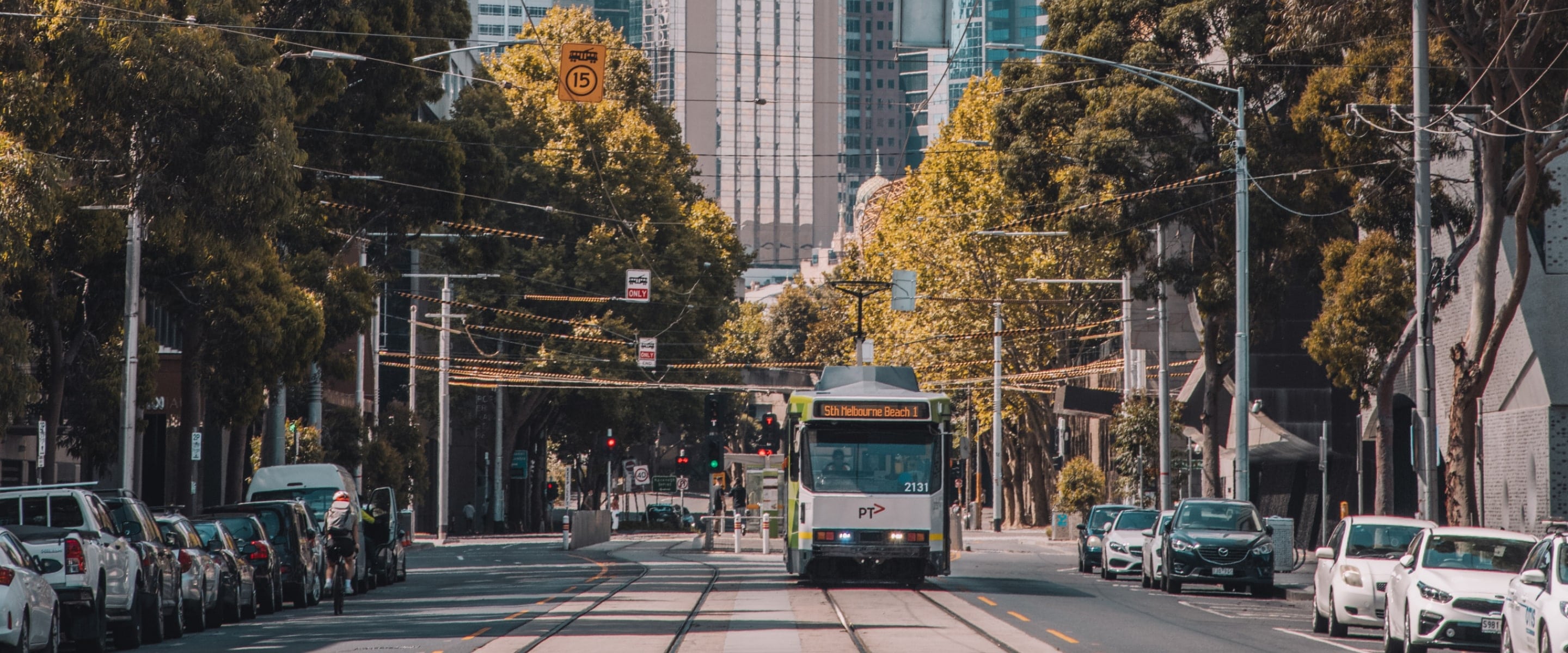 Modern Melbourne trams coming down tree lined street in the CBD