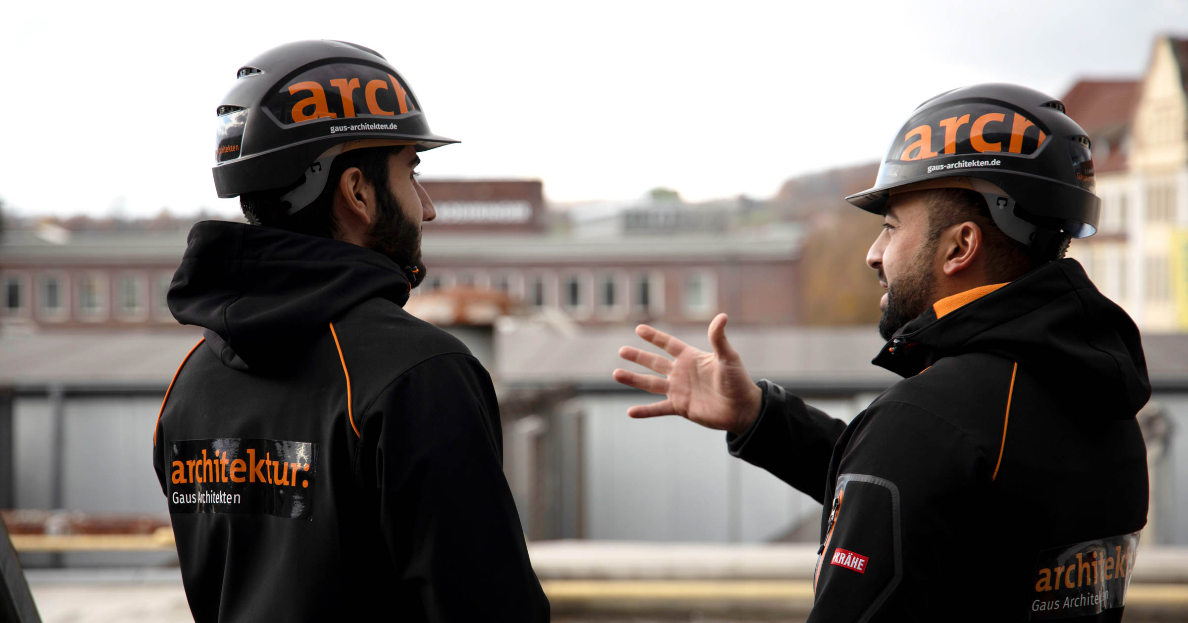 Zwei Männer mit Bauhelmen diskutieren auf der Baustelle.