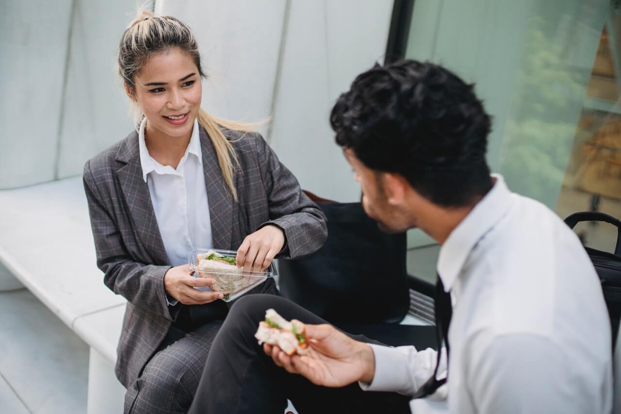 How to Eat Healthy While Traveling for Work - A man and women eating sandwiches together